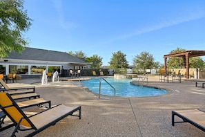 Ein Swimmingpool mit Liegestühlen und einer Pergola, umgeben von einem Zaun und Bäumen.