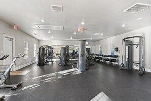 Une salle de sport équipée de machines de cardio, d’appareils de musculation et d’haltères.