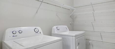 A laundry area with two white Amana washing machines and metal drying racks.