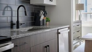 Eine moderne Küche mit einer Edelstahl-Spüle, einem schwarzen Wasserhahn und einer Granitarbeitsplatte.