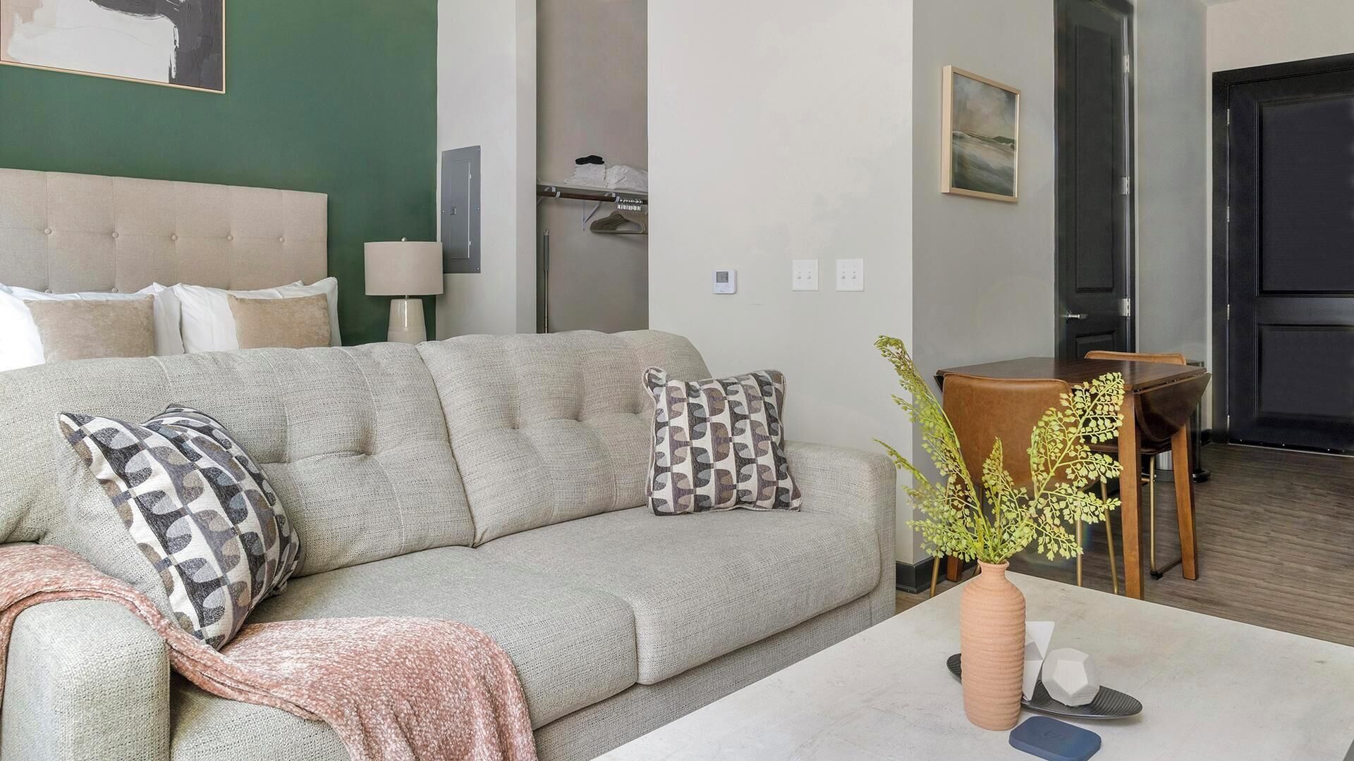 A living room with a sofa, a coffee table, and a dining area with a table and chairs.