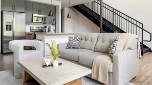 Ein modernes Wohnzimmer mit einer Couch, einem Couchtisch und einer Küche im Hintergrund.