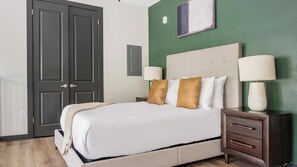 Ein Hotelzimmer mit Bett, Nachttischlampen, einem Nachttisch und einer Wand in Grünton.