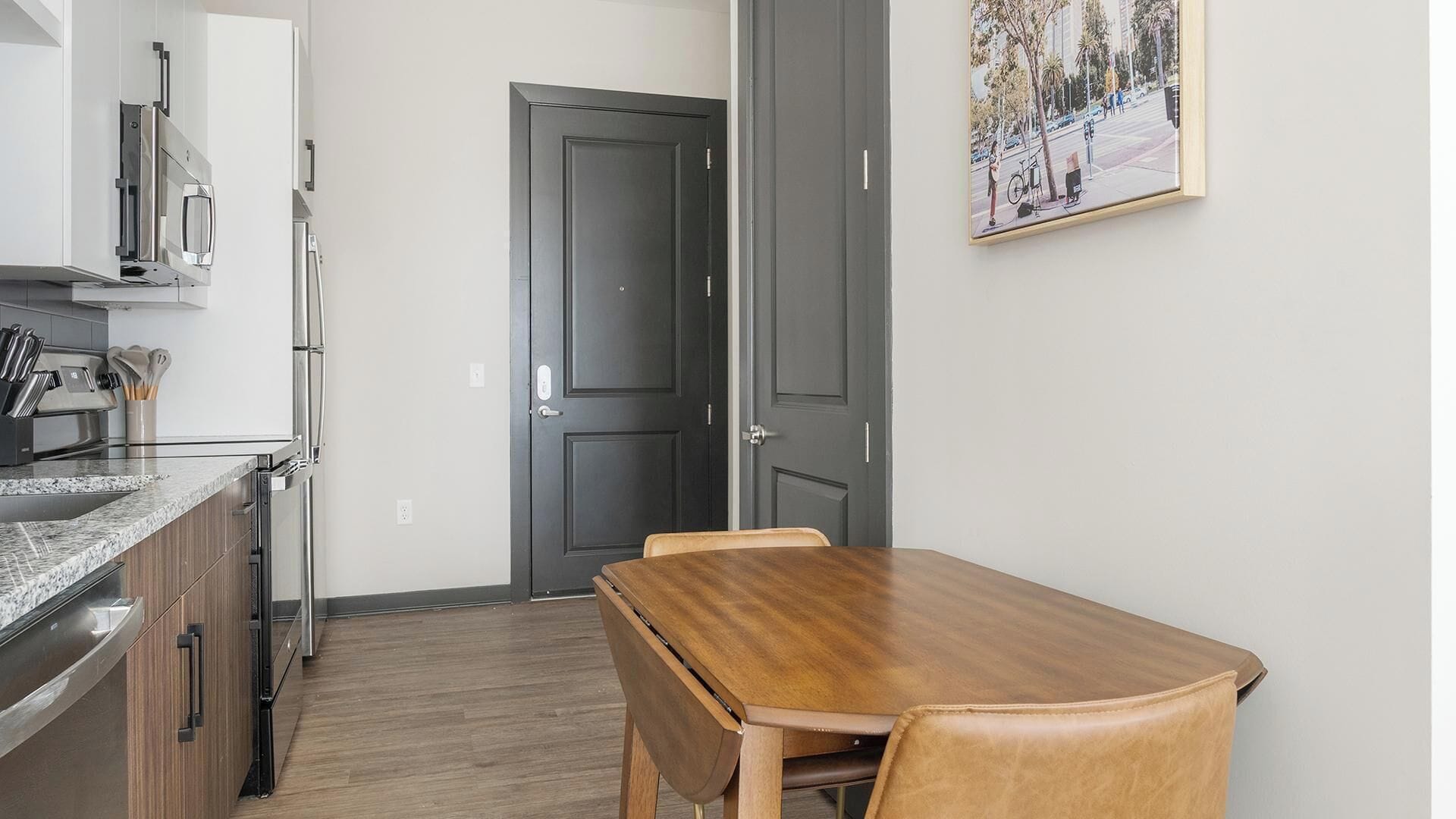 A compact kitchen with modern appliances, a dining table with chairs, and a door leading to another room.