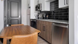 Eine moderne Küche mit Esstisch und Stühlen aus Holz, Edelstahlgeräten und einer schwarzen Küchenzeile.