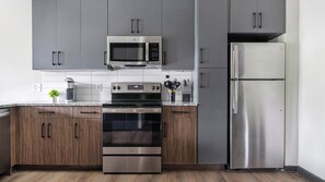 Eine moderne Küche mit Edelstahlgeräten, Holzschränken und einer Arbeitsplatte aus Granit.