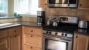 A kitchen with wooden cabinets, a stainless steel stove, a microwave, and a kettle. - Olive Alley by Avantstay Outdoor Dining + Full Kitchen Downtown Paso Robles Wine Country (Paso Robles)
