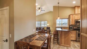 A spacious kitchen with wooden cabinets, a dining area with a large table and chairs, and a ceiling fan.