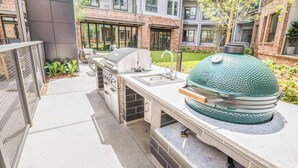 An outdoor kitchen area with a grill, sink, and seating. - Landing | Spectacular 1BD, Gym, Courtyard (Atlanta)