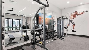 A gym with various exercise equipment, mirrors, and a motivational wall mural. - Landing | Spectacular 1BD, Gym, Courtyard (Atlanta)