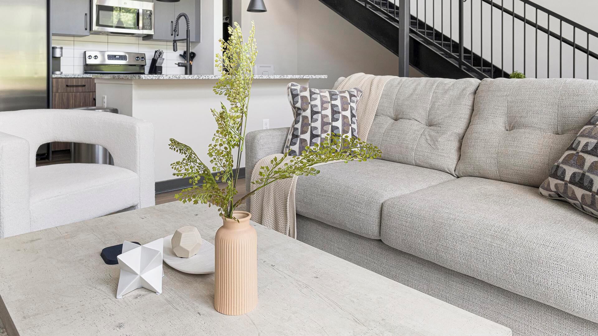 A modern living room with a sofa, a coffee table, and a vase with a plant.