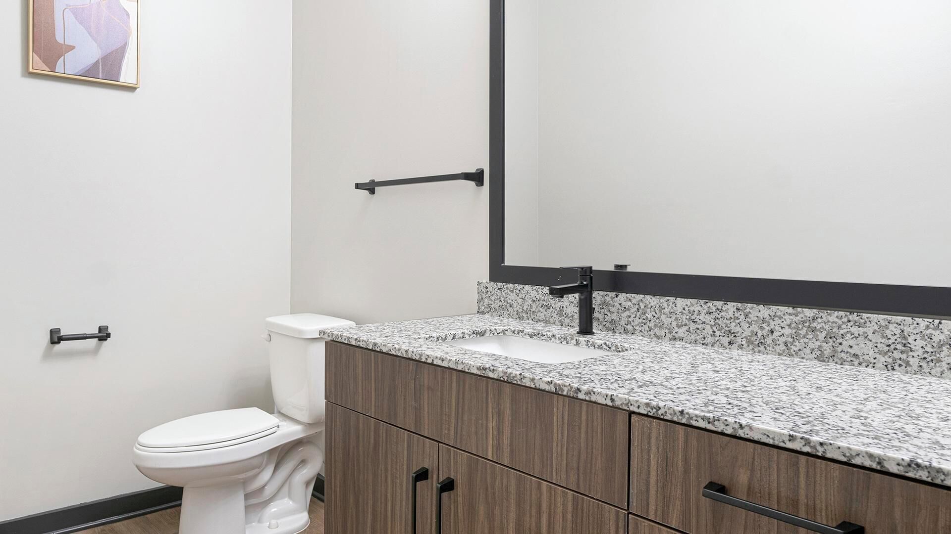 Een badkamer met toilet, wastafel en spiegel.