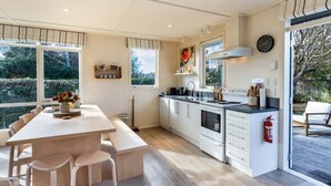 Eine moderne Küche mit Essbereich, großen Fenstern und Blick ins Freie.