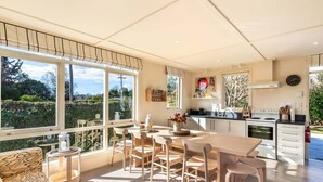 Eine moderne Küche mit Essbereich, großen Fenstern und Blick ins Freie.