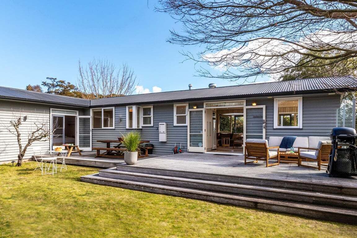 Een tweelaags huis met een patio, tuinmeubilair buiten en een kleine tuin.
