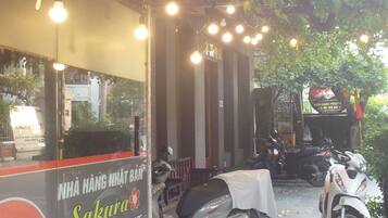 Restaurante com área externa, luzes de fada e scooters estacionadas.