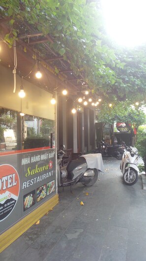 Restaurante com área externa, luzes de fada e scooters estacionadas.