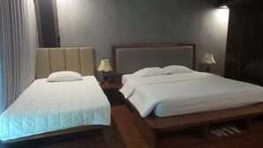 Une chambre d’hôtel avec deux lits, une tête de lit en bois, une table de chevet avec une lampe et une fenêtre avec des rideaux.