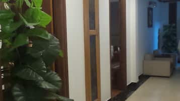 Un pasillo con una planta en maceta, puertas de madera y suelo de baldosas.