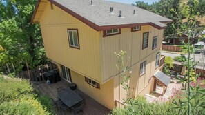 Ein zweistöckiges Haus mit einer Terrasse, einer überdachten Veranda und einem Garten.