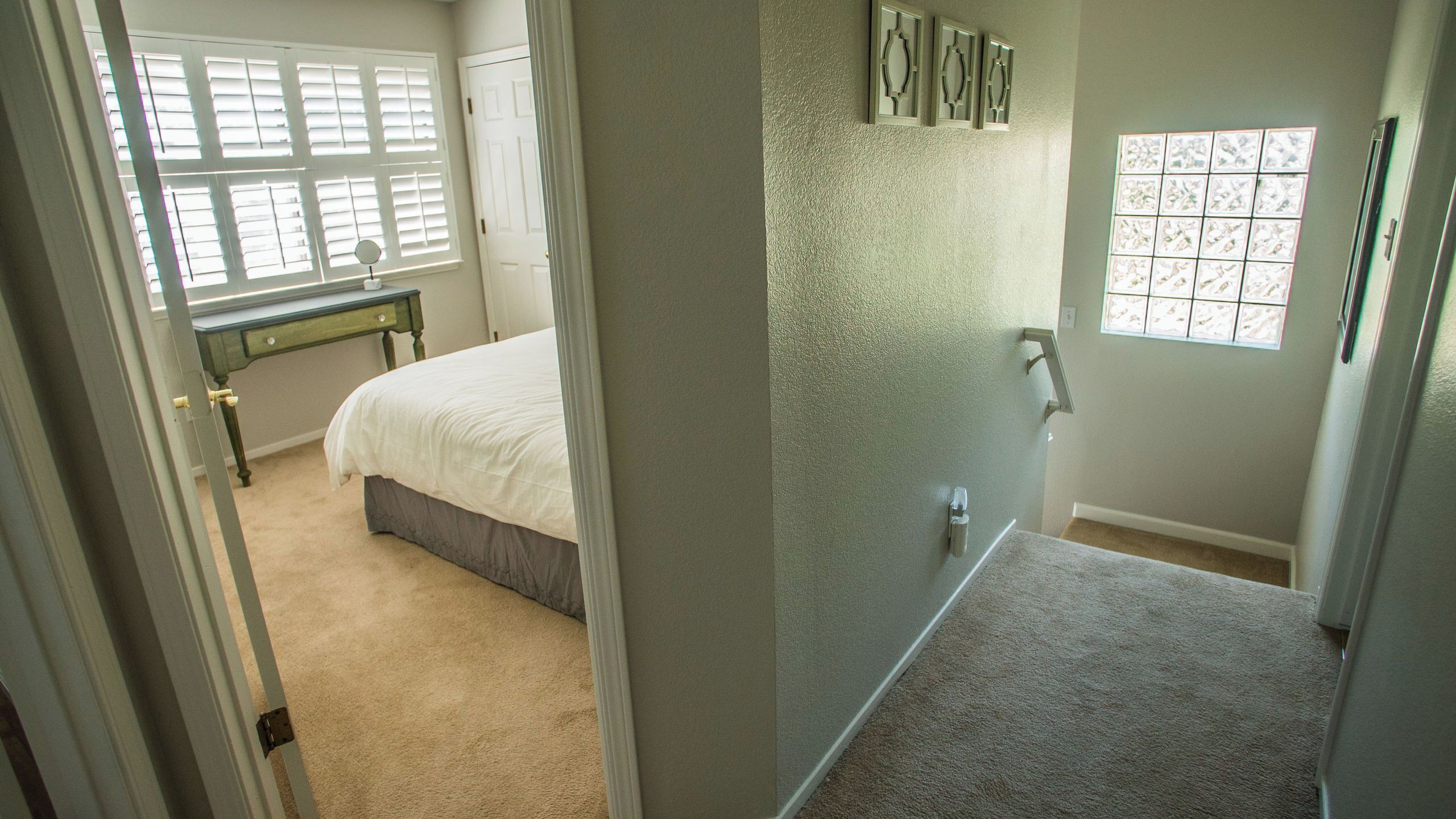 A bedroom with a bed, a dresser, a window with blinds, and a door.