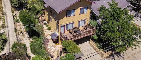 A two-story house with a balcony, surrounded by greenery.