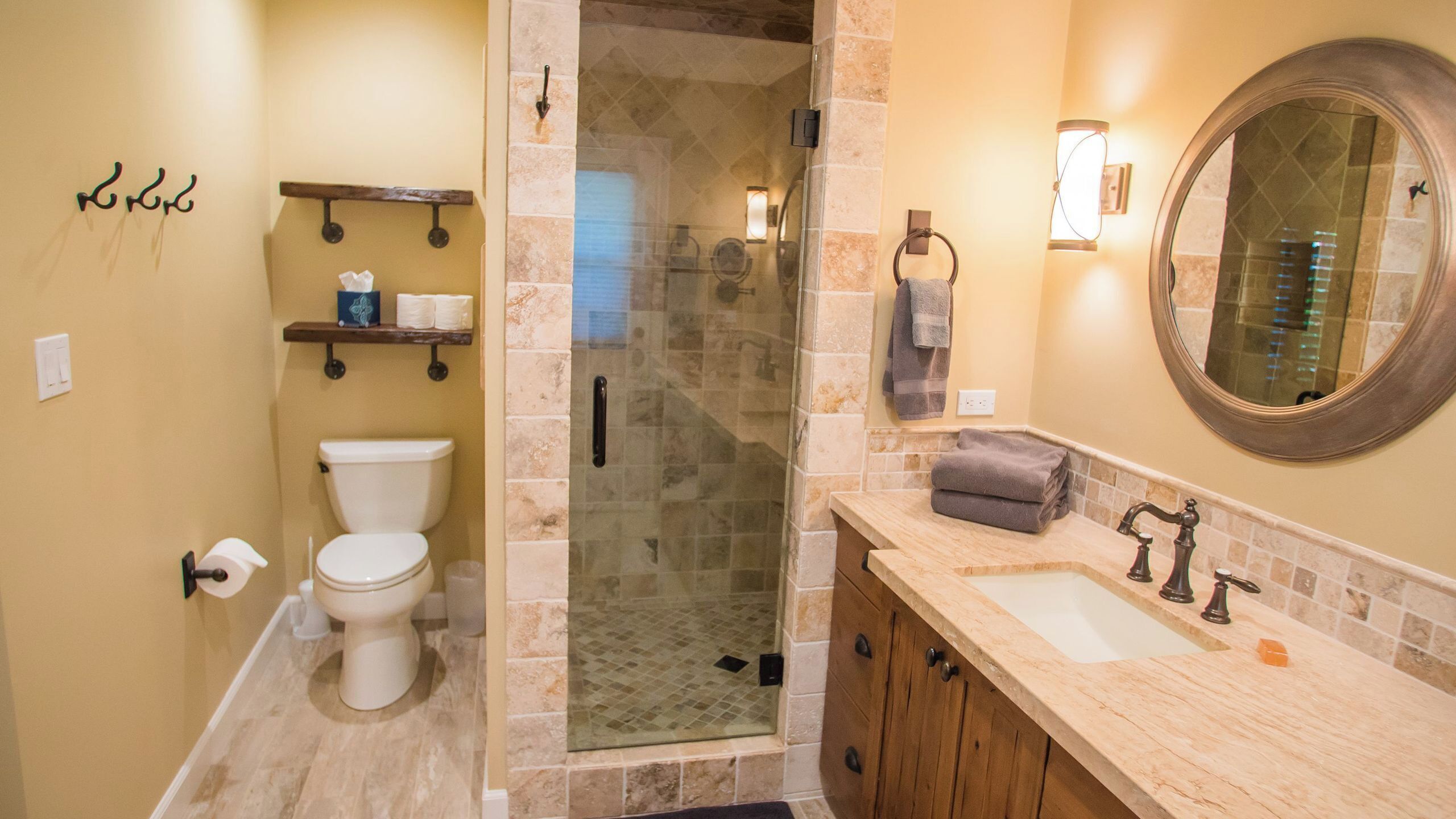 A bathroom with a toilet, a shower enclosure, a sink, and a mirror.
