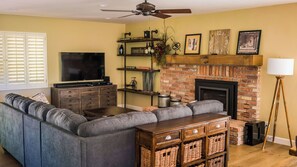A living room with a sectional sofa, a flat-screen TV, a fireplace, and a ceiling fan. - Hilltop West by Avantstay Deck Grill + Game Lounge Paso Robles Wine Country (Paso Robles)