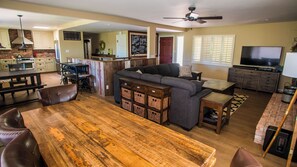 A spacious living area with a wooden dining table, leather chairs, a gray sofa, and a television. - Hilltop West by Avantstay Deck Grill + Game Lounge Paso Robles Wine Country (Paso Robles)