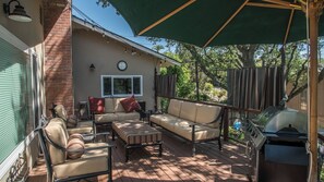 Eine überdachte Terrasse mit Gartenmöbeln, einer Uhr und einem Grill.