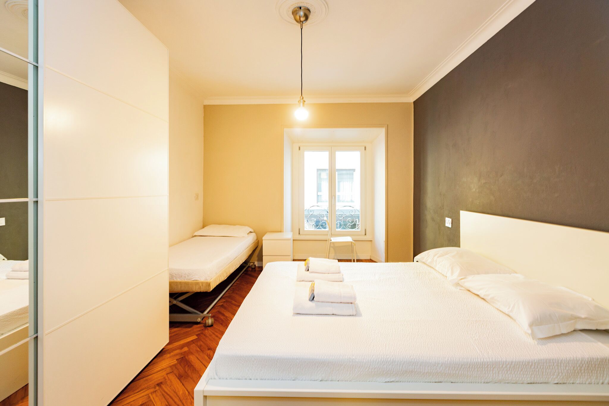 Een slaapkamer met een bed, een tafeltje en een raam.