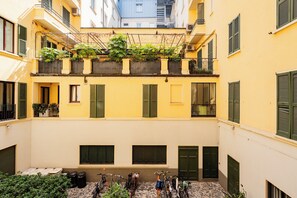 A courtyard with a yellow building, green shutters, and a bike rack with several bicycles. - Buenosaires5 Elegance in Porta Venezia by Hospity (Milan)
