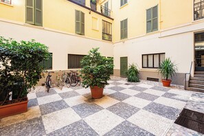 Ein Innenhof mit Fliesenboden, Blumentöpfen und Fahrrädern.