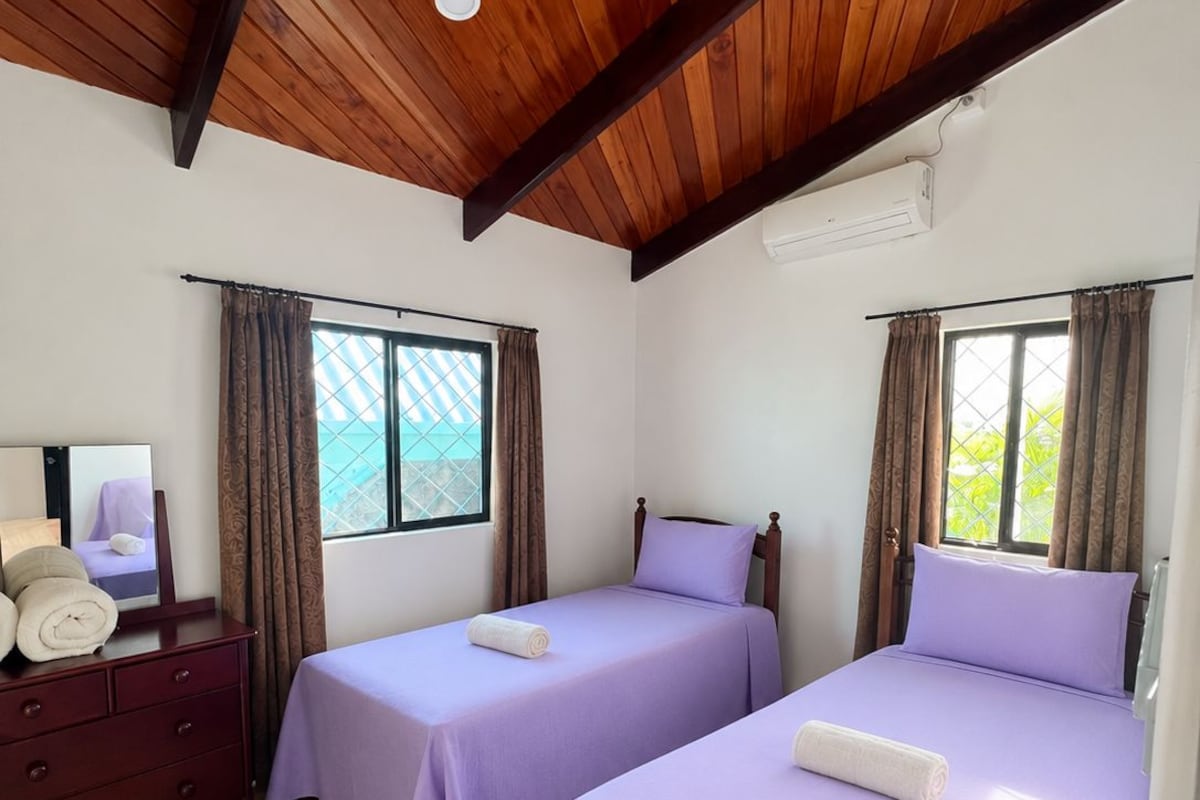 A room with two beds, a dresser, and a window with curtains.
