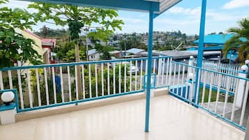 Varanda com chão de azulejos, guarda-corpo azul e vista para uma área residencial.