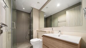 A modern bathroom with a glass shower enclosure, a toilet, a vanity with a mirror, and a sink. - 2-bedroom apartment in peaceful Buiness Bay with fitness room and AC (Buiness Bay)