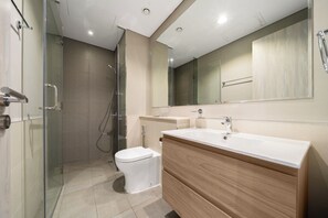 Ein modernes Badezimmer mit Duschkabine aus Glas, Toilette, Waschtisch mit Spiegel und Waschbecken.