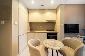 Eine kompakte Küche mit Essbereich, inklusive eines kleinen Tisches und zwei Stühlen, einem an der Wand befestigten Fernseher und einem eingebauten Backofen.