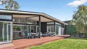 A modern house with a covered patio, a lawn, and a dining area with outdoor furniture. - 4 bedroom house with Spa short walk to the square (Martinborough)
