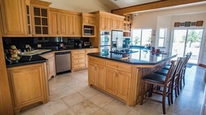 A kitchen with wooden cabinets, a dishwasher, a microwave, an oven, and a large island with bar stools. - Uvae Vineyard by Avantstay Jetted Tubs + BBQ Patios Paso Wine Country (Paso Robles)