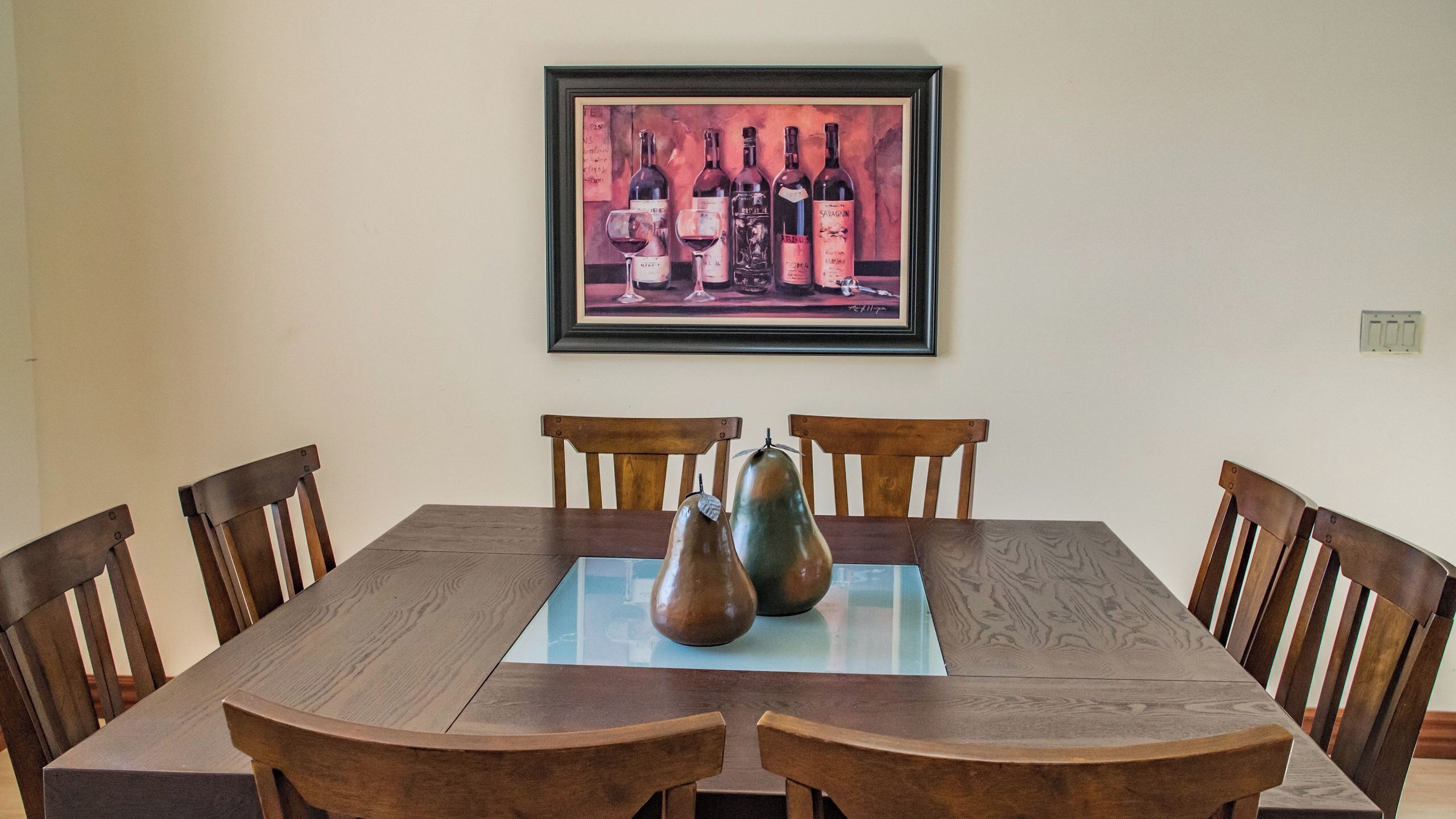 A dining table with six wooden chairs, a glass top, and two ceramic vases.