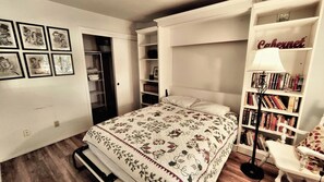 Ein Schlafzimmer mit Bett, Bücherregal, Schreibtisch und Kleiderschrank.