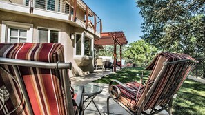 Eine Terrasse mit gestreifter Gartenmöbel, einer Pergola und Blick auf ein Gebäude mit Balkon.