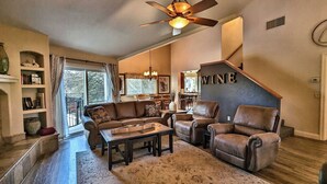 A spacious living room with a large window, a ceiling fan, and a staircase leading to another level. - Candlewood Creek by Avantstay Pool + Fire Pit Quiet Paso Cul-de-sac (Paso Robles)
