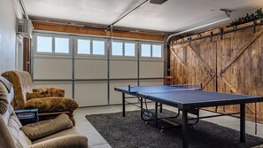 Une table de ping-pong dans un garage, avec un mur en bois et une chaise.