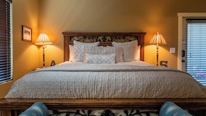 A neatly made bed with a patterned bedspread, two bedside lamps, and a wooden headboard with intricate designs. - Hope's Place by Avantstay Hilltop Views + Game Room Near Lake Nacimiento (Paso Robles)