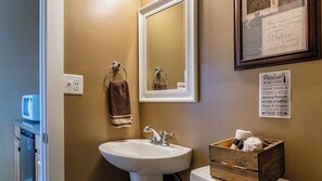 A bathroom with a sink, mirror, towel rack, and a sign listing amenities like paper towels and tissues. - Hope's Place by Avantstay Hilltop Views + Game Room Near Lake Nacimiento (Paso Robles)