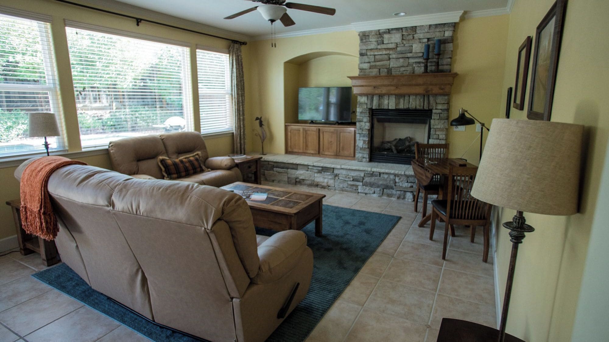 A living room with a beige sofa, a coffee table, a fireplace, and a stone accent wall.