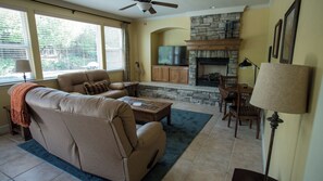 A living room with a beige sofa, a coffee table, a fireplace, and a stone accent wall. - Navajo Trail by Avantstay Lap Pool + Spa Steps to Salinas River Trail (Paso Robles)
