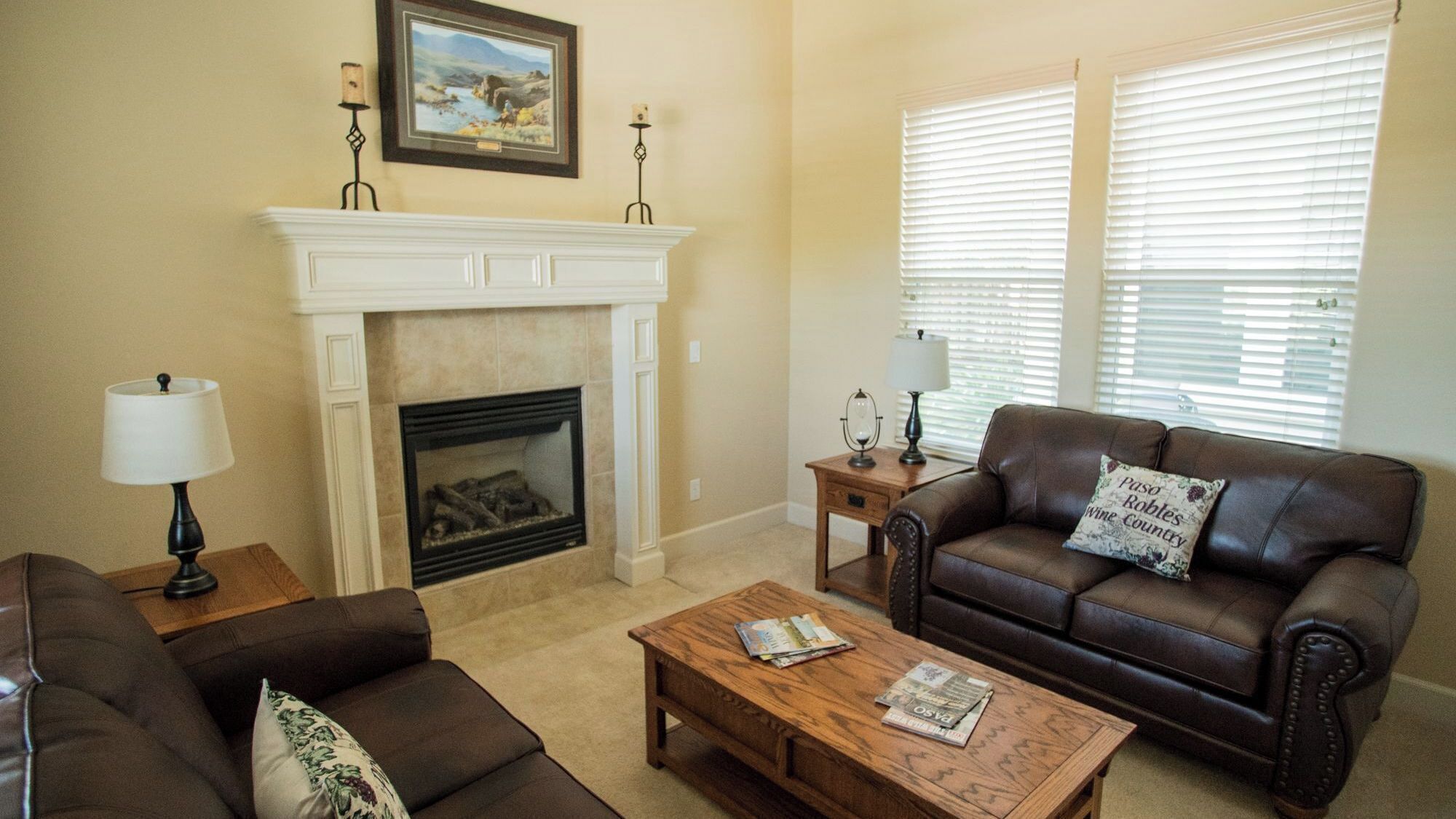 A living room with a fireplace, two sofas, a coffee table, and a window with blinds.